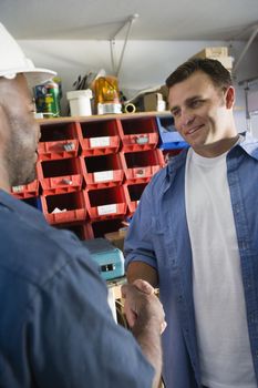 Industrial worker shaking hand with his colleague at workplace
