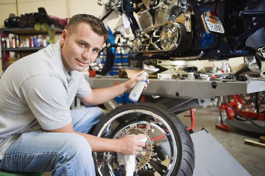 Portrait of a male mechanic working on a tire at workplace