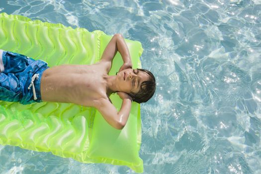 Boy Floating in Swimming Pool on Inflatable Mattress