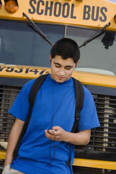 Teenager Boy Listening to MP3 Player by School Bus