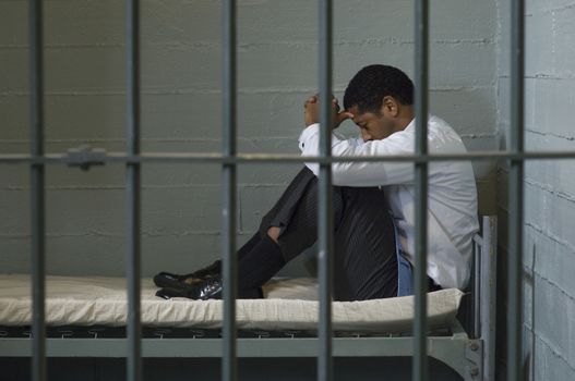 Mature man sitting on bed in prison cell