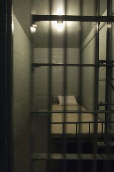 Interior of empty prison cell with bed in it