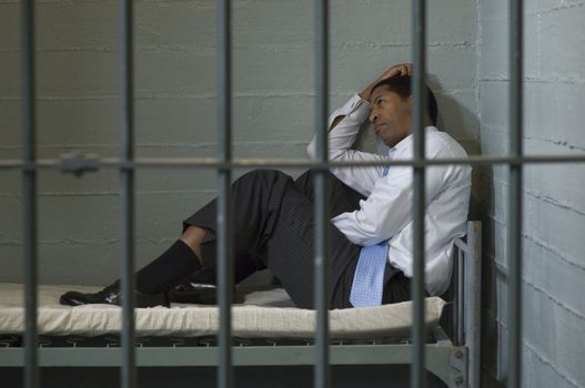 Mature man sitting on bed in prison cell
