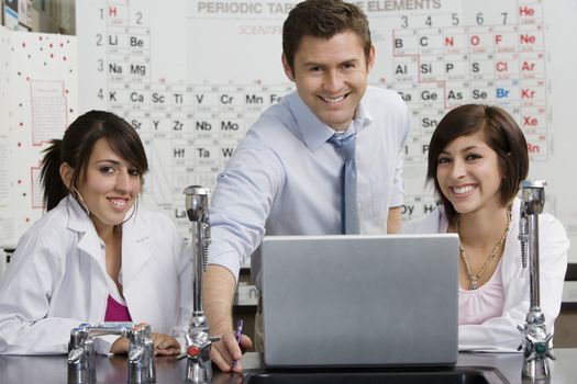 Portrait of happy teacher with high school students in science class