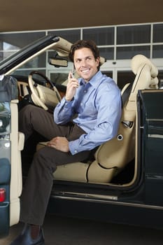 Man sitting in a convertible communicating on cell phone