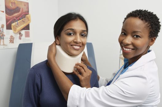 Portrait of a friendly doctor putting brace on Indian patient's neck