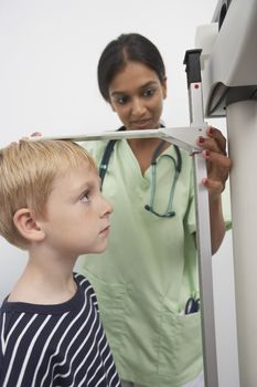 Female doctor measuring height of a boy in the clinic