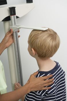 Female nurse measuring boy's height in the clinic