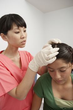 Nurse checking girls head in hospital