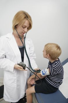Female doctor taking blood pressure of boy