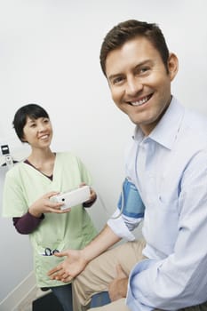 Doctor checking male patients blood pressure in hospital