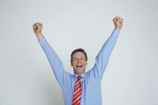 Studio portrait of businessman smiling with arms raised