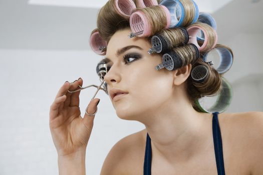 Model in Hair Curlers Using Eyelash Curler