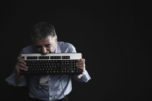 Worried Businessman Biting a Computer Keyboard