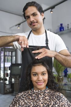 Portrait of barber cutting young womans hair
