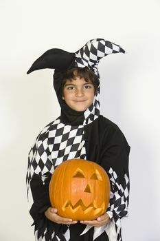Portrait of boy (7-9) wearing jester costume with jack-o-lantern