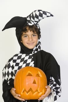 Portrait of boy (7-9) wearing jester costume with jack-o-lantern