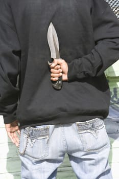 Man holding knife behind back