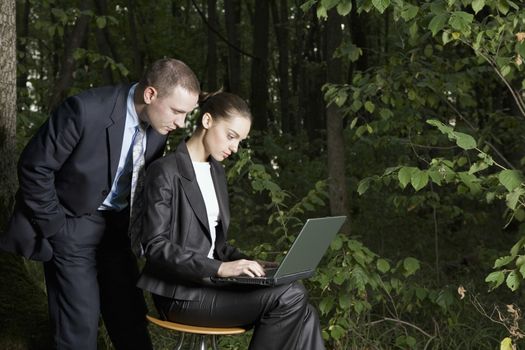 Business couple using laptop in forest