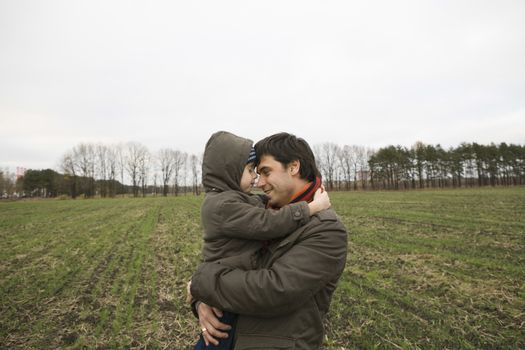 Father embracing son in field