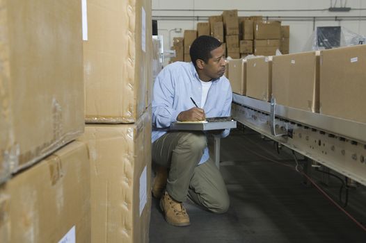Man inspecting boxes on conveyor belt in distribution warehouse