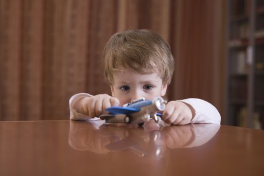 Little boy playing with toy airplane on table at home