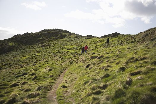 Three adults climbing a hillside