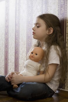 Girl with doll sitting in home