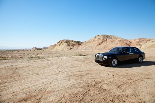 Rolls Royce car parked on unpaved road in front of mountains