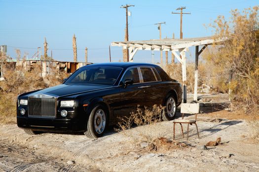 Rolls Royce parked next to broken chair in abandoned village