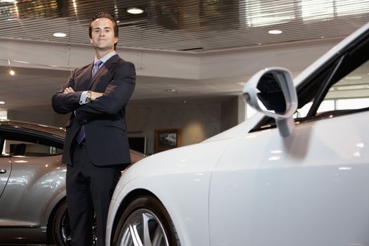 Confident car salesperson standing with arms crossed