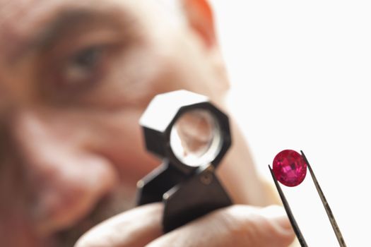 Close up of gemstone with jeweler looking through magnifying glass
