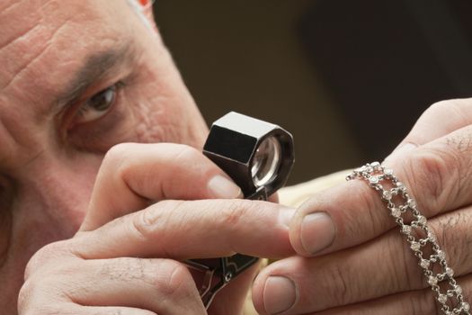 Close up of man looking at jewelry through magnifying glass