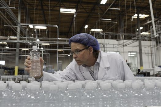 Quality control worker checking bottled water at bottling plant
