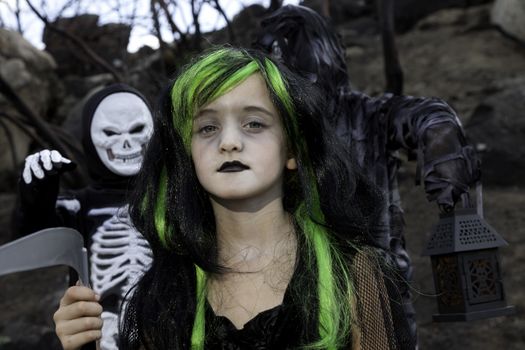 Portrait of girl dressed up as witch while her friends dressed up in skeleton costume