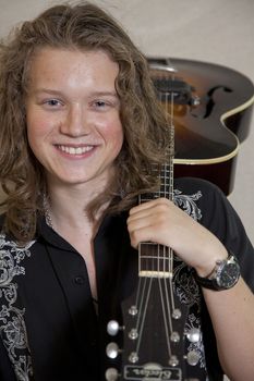 Portrait of smiling young musician with guitar over shoulder
