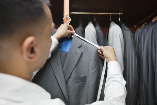 Tailor measuring shoulder of the suit