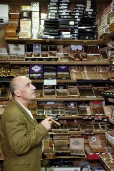 Mature tobacco shop owner looking at cigars on display