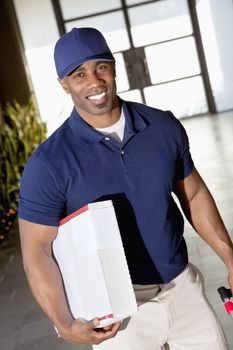 Tilt image of a happy African American delivery man looking at camera
