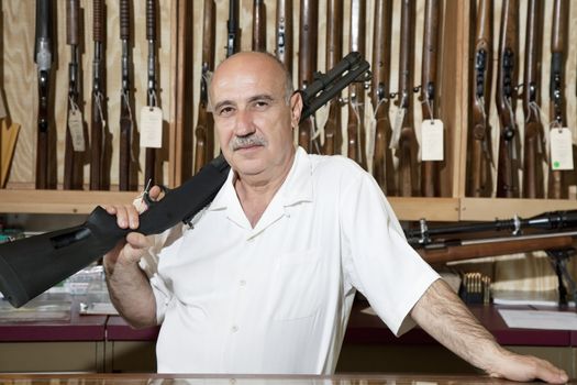 Portrait of a mature man with rifle on shoulder in gun store