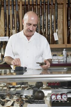 Mature male merchant at gun shop with credit card reader