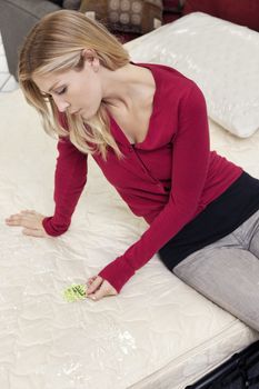 Young woman sitting mattress while looking at price tag
