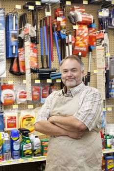 Portrait of a confident mature salesperson with arms crossed in hardware store