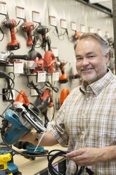 Portrait of a happy hardware store owner with electric saw