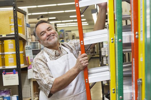 Portrait of a happy mature man with ladder in hardware store