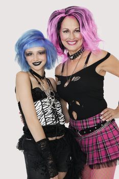 Portrait of happy senior and young punk females over gray background