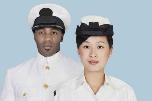 Portrait of two multi-ethnic US Navy officers over light blue background