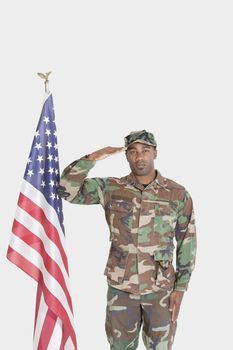 Portrait of US Marine Corps soldier saluting American flag over gray background