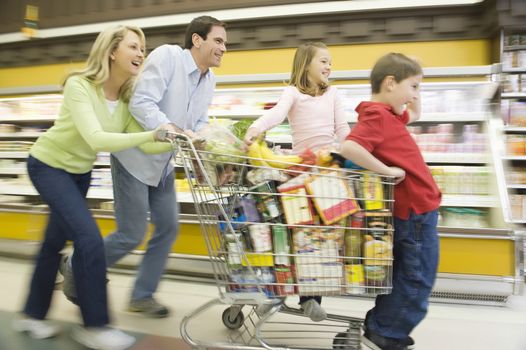Family of four run with full shopping trolley