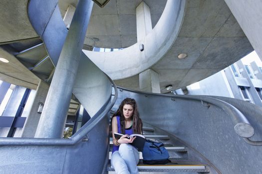 University student reading on staircase